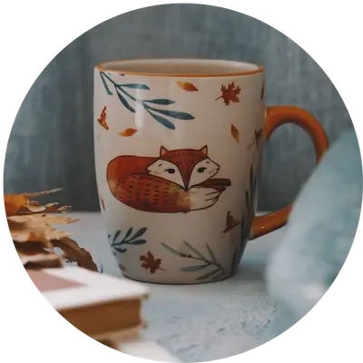 Bemalter Keramikbecher mit Fuchsmotiv und bleibendem Wert gefüllt mit Kaffee auf einem Tisch