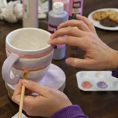 Keramik Bemalen 1 Hände bemalen eine Keramiktasse mit Streifen bei einem Keramik bemalen Workshop
